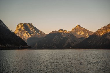 Avusturya 'da bir gölün üzerinde sonbahar günbatımı, gün batımında güzel manzara fotoğrafçılığı