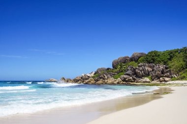 Beyaz kum, palmiye ağaçları, Granit kayalar ve turkuaz su