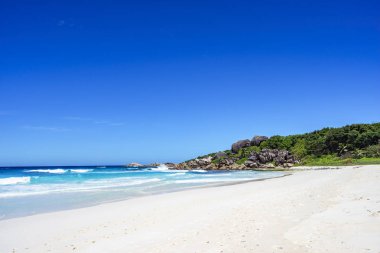 Beyaz kum, palmiye ağaçları, Granit kayalar ve turkuaz su