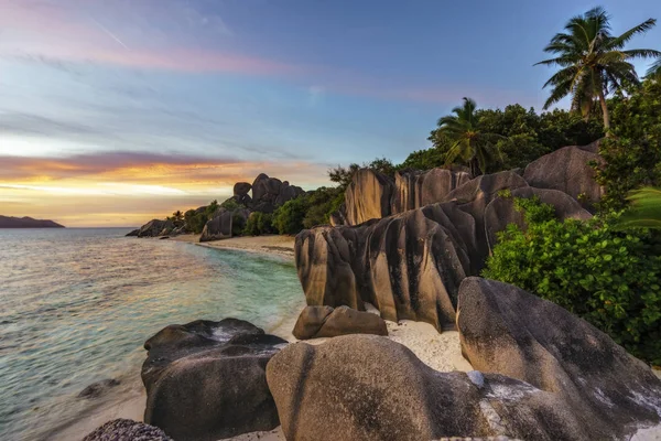 Zonsondergang over rotsen, palmen, zand en turquoise water op tropisch strand, l — Stockfoto