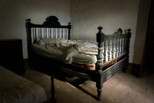 Lonely and dark room with a vintage and creepy bed. - Stock Image -  Everypixel