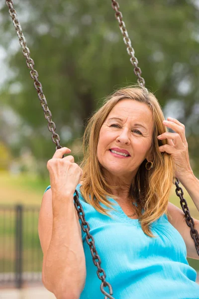 Happy friendly senior woman on swing outdoor — Stock Photo, Image