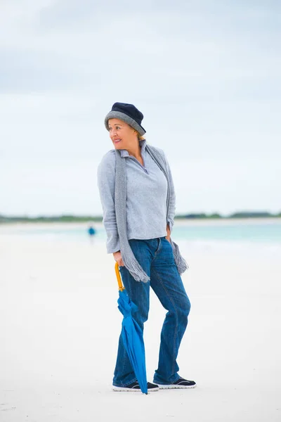 Avslappnad mogen kvinna med paraply ocean bakgrund — Stockfoto