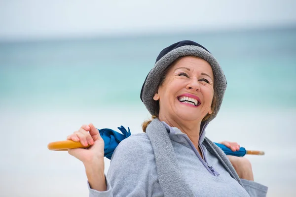 Happy mature woman with umbrella ocean background — Stock Photo, Image