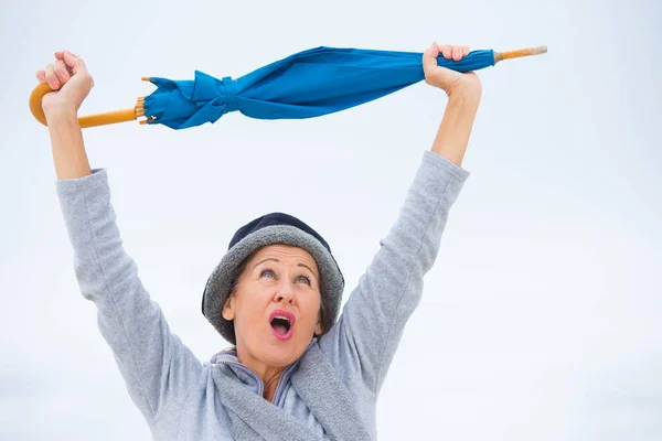 Happy mature woman with umbrella arms up — Stock Photo, Image