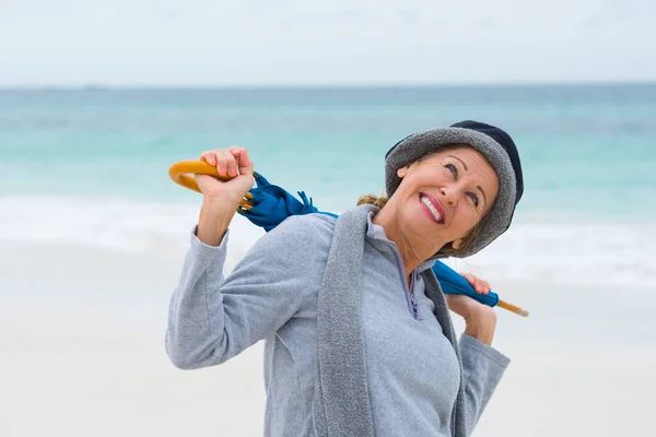 Glücklich reife Frau mit Sonnenschirm Strand Hintergrund Stockfoto