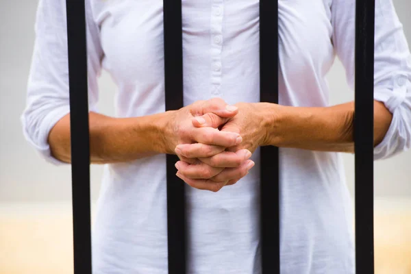Mulher com as mãos atrás das grades na prisão — Fotografia de Stock