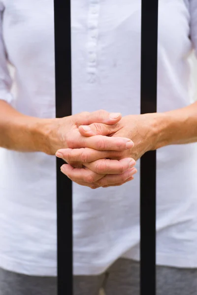 Mujer con las manos entre rejas en la cárcel — Foto de Stock