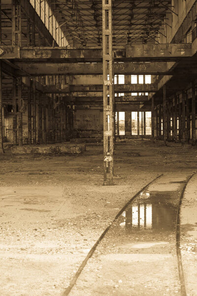 Antique filtered Interior view of dirty old abandoned vandalised factory ruin, deserted hall, rusty steel structure, copy space.