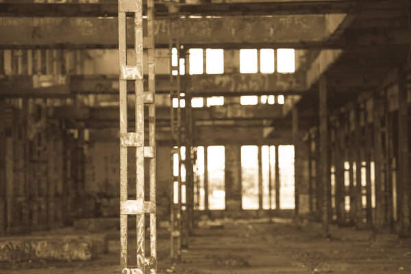Antique filtered Interior view of dark dirty old abandoned vandalised factory ruin, deserted hall, rusty damaged steel structure, graffiti, copy space.