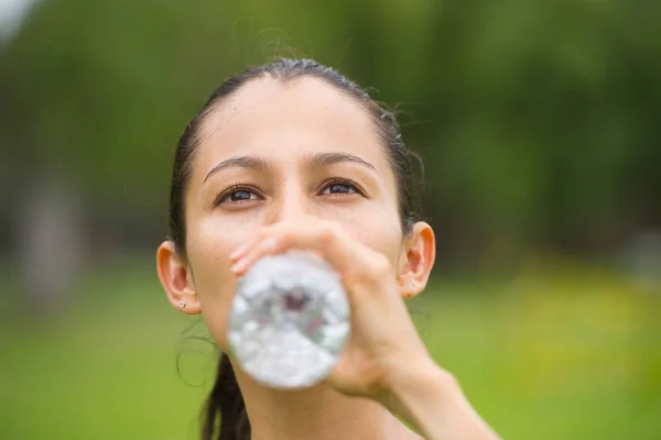若いアクティブな女性は屋外の水を飲む — ストック写真