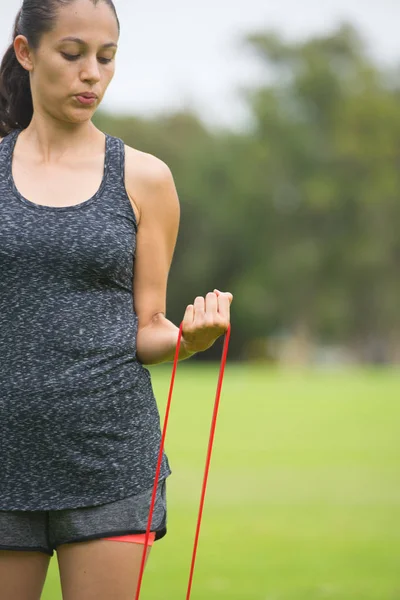 Jonge vrouw rekken fitness band uit te oefenen buiten — Stockfoto