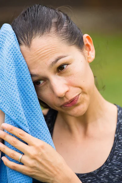 スポーティな疲れ若い女性がタオルを屋外で ストック写真