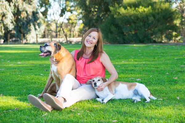 犬ペットを持つ成熟した女性が公園でリラックス — ストック写真