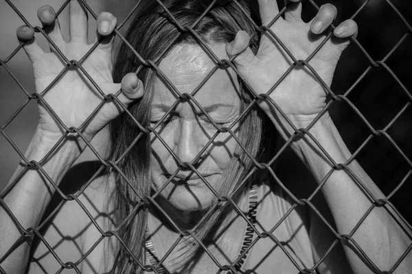 Desesperada triste mujer infeliz detrás de la cerca —  Fotos de Stock