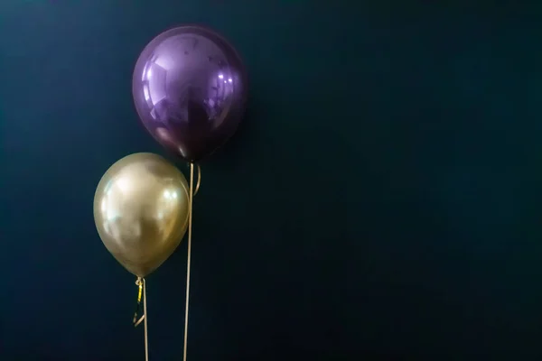 Balão dourado e balão violeta em um fundo escuro. Conceito de férias, cartão postal — Fotografia de Stock