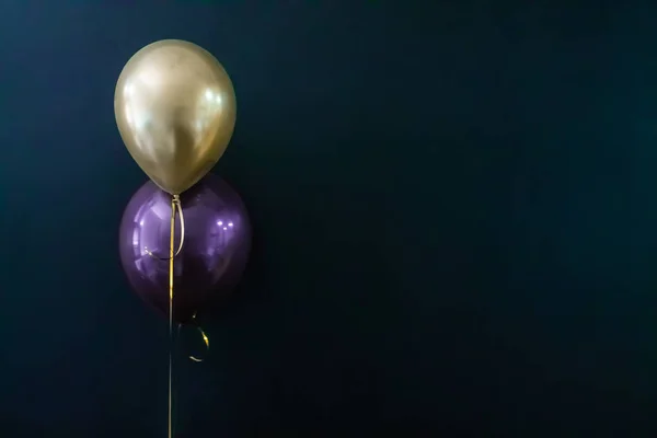 Balão dourado e balão violeta em um fundo escuro. Conceito de férias, cartão postal — Fotografia de Stock