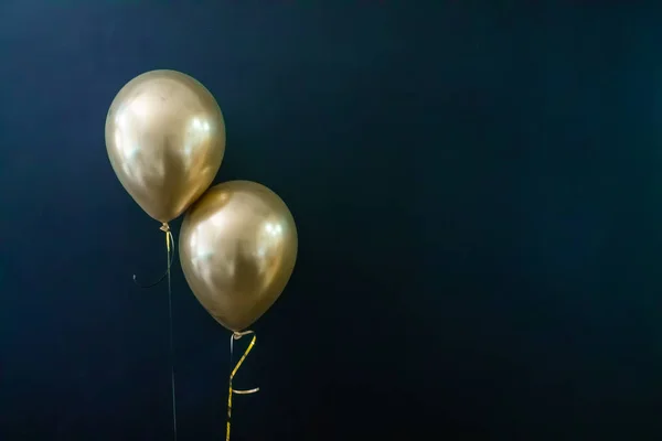 Dois balões dourados num fundo escuro. Conceito de férias, cartão postal — Fotografia de Stock