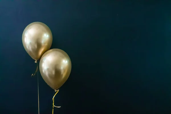 Dois balões dourados num fundo escuro. Conceito de férias, cartão postal — Fotografia de Stock