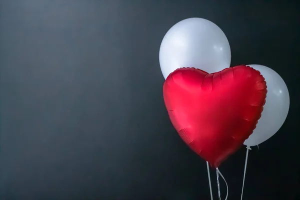 Czerwony balon w kształcie serca i białe okrągłe balony na czarnym tle. Walentynki, wakacje, miłość. — Zdjęcie stockowe