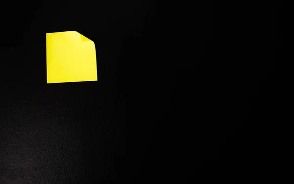 Adesivo de escritório amarelo em uma parede preta . — Fotografia de Stock