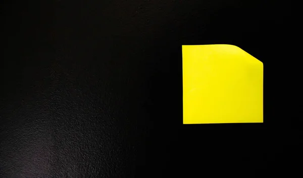 Adesivo de escritório amarelo em uma parede preta . — Fotografia de Stock