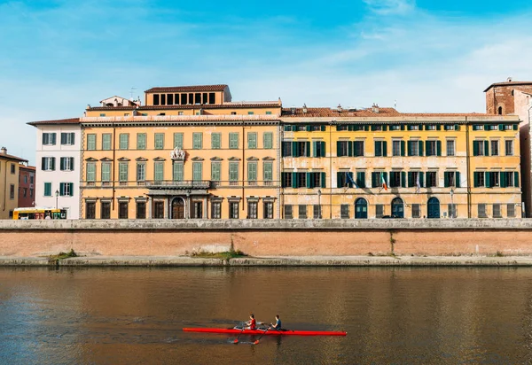 Ruderer auf dem Fluss Arno in Pisa, Toskana, Italien mit atemberaubender farbenfroher italienischer Architektur im Hintergrund — Stockfoto