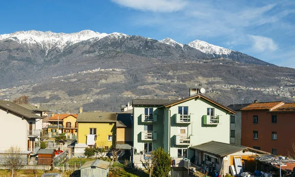 Edifícios residenciais em primeiro plano com majestosos alpes italianos em segundo plano, capturados perto de Sondrio em Valtellina - Itália — Fotografia de Stock