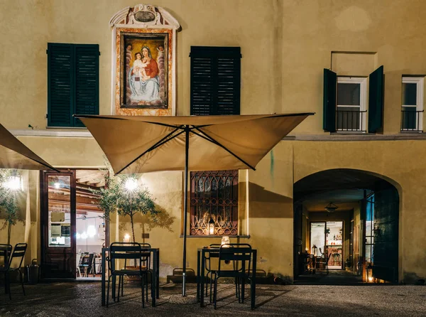 De ingang van het restaurant met terras tafels en religieuze muurschildering in Italië — Stockfoto