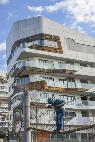 Menino pequeno de 4-6 anos joga em uma corda apertada montada em um playground no Tre Torri Citylife distrct de Milão, Itália durante um dia ensolarado de inverno — Fotografia de Stock