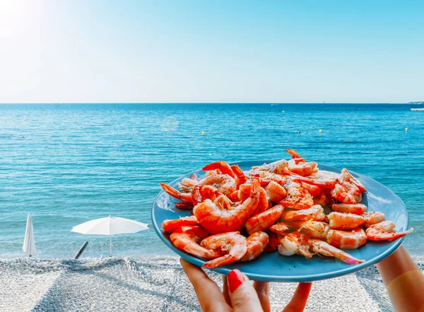 Langostinos o camarones en un plato al borde de la hermosa playa mediterránea —  Fotos de Stock