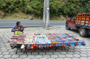 Local indigenous Ecuadorian man plays the banjo while selling local handicrafts on side of road clipart