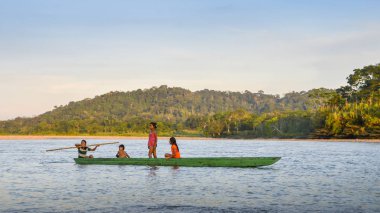 Local Quechua tribe teenagers in the Ecuadorian Amazon on a canoe on the river Napo clipart