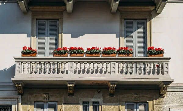 Μπαλκόνι με ήλιο και τα όμορφα κόκκινα λουλούδια. Συλλαμβάνονται σε Μιλάνο — Φωτογραφία Αρχείου