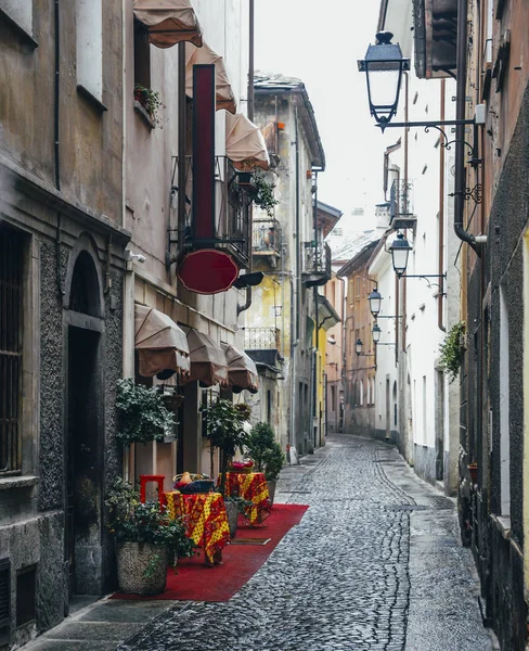 Quaint cobblestone alleyway in Aosta Italy with inviting red carpet entrance to Italian restaurant on left — Stock Photo, Image