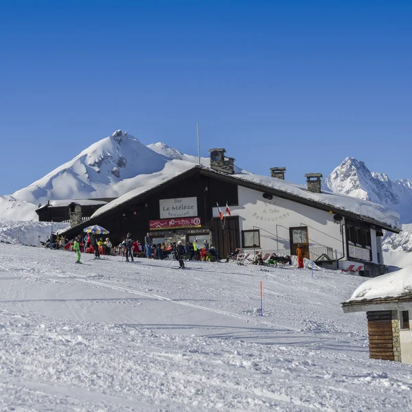 Skiers and snowboarders next to a wooden cabin in the Italian Alps during the winter, with copy space — Stock Photo, Image