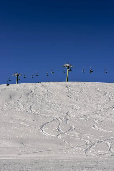 Winding snowboard trace and chairlift shadow on white snow — Stock Photo, Image