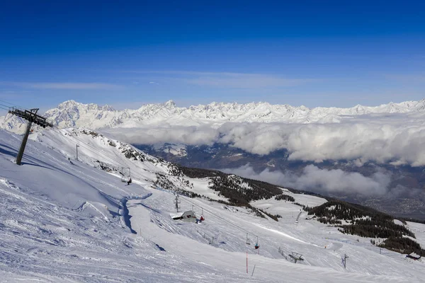 Chairlift at Italian ski area of Pila on snow covered Alps and pine trees during the winter with Mt. Blanc in France visible in background - winter sports concept — Stock Photo, Image
