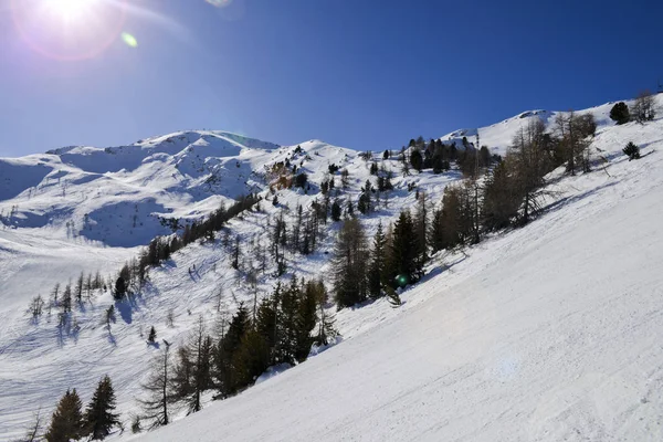Steep gradient piste in Italian Alps, against a beautiful blue sky and sun flares — Stock Photo, Image