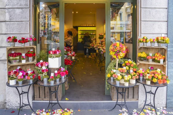 Buiten een winkel bekijken terwijl assistenten bloemen bij een bloemist specialist in Milaan, Italië rangschikt — Stockfoto