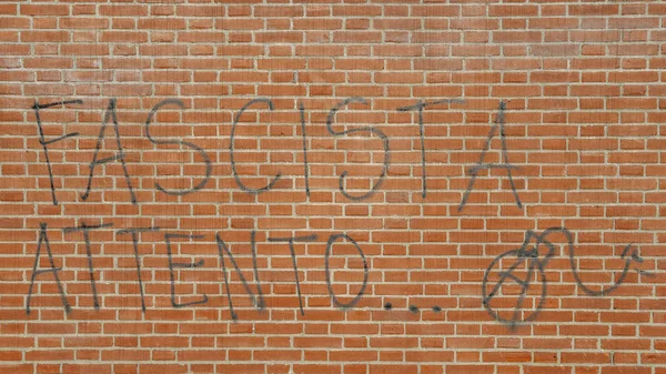 Graffiti na ścianie z czerwonej cegły w włoski mówiąc Fascisti Attento z bomby i A, przetłumaczone na zagrożenie faszystów Uważaj - antifa według tematu — Zdjęcie stockowe