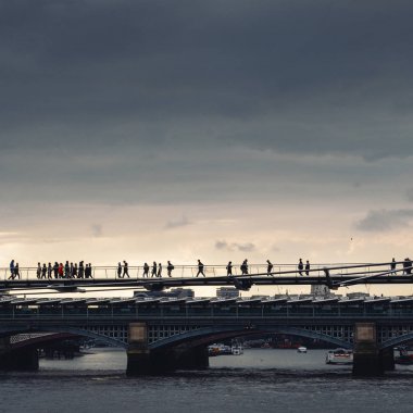 Backlit silhouette of unidentifiable pedestrians on the Millennium Bridge in London, England, UK. clipart