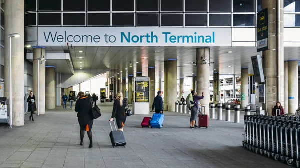 Sign welcoming passengers to London Gatwick's North Terminal servicing destinations in Europe and beyond. Passengers and air crew on foreground — Stock Photo, Image