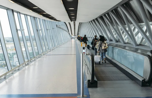 Passagerare med bagage gå på en lång horisontell rulltrappa som omfattas av en modern tunnel på London Gatwicks norra Terminal — Stockfoto