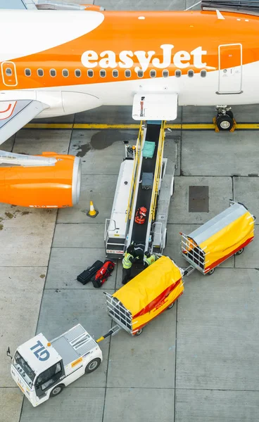 Londra Gatwick'ın Kuzey terminalde Airbus A320 easyjet uçak Bagaj işleyicileri bir Konveyör bant üzerinden bavul toplayıp yüksek bakış bağlı — Stok fotoğraf