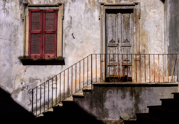 Traditionele zon-verlicht rustieke Italiaanse architectuur gevel met trappen naast ijzeren leuning leidt tot versleten trappen en houten deur. — Stockfoto