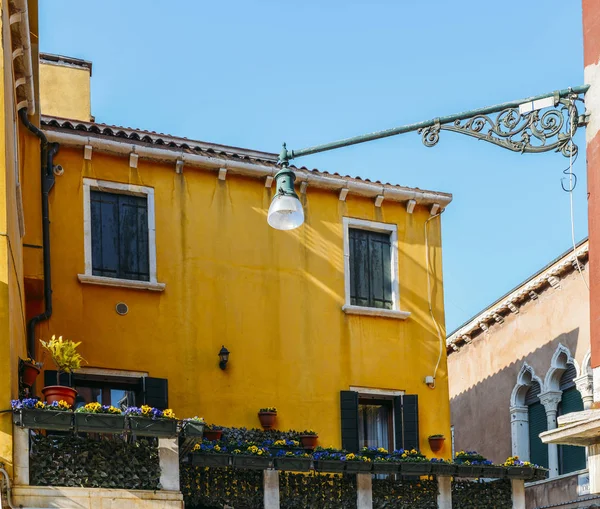 Casa gialla con fiori e panca. Case colorate nell'isola di Burano vicino a Venezia. Cartolina di Venezia. Luogo famoso per il turismo europeo e viaggi . — Foto Stock