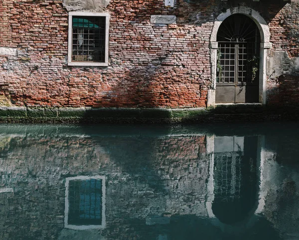 Фасадні частково mossy старий цегляний будинок з дерев'яні старовинні двері на вузьким каналом у Венеції, Італія. — стокове фото
