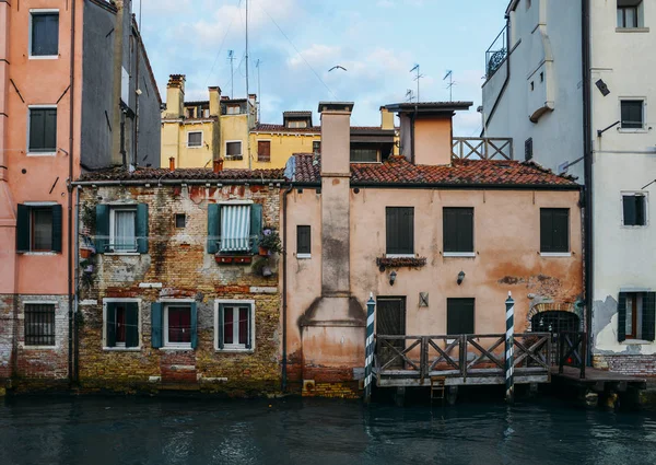 Фасадні частково mossy старий цегляний будинок з дерев'яні старовинні двері на вузьким каналом у Венеції, Італія — стокове фото