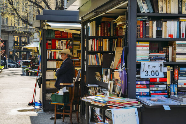 An older man with a cowboy hat sells books on the street Stock Picture